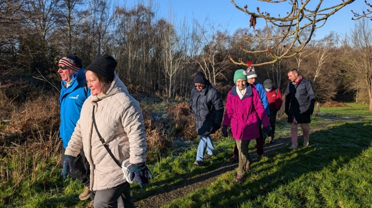 A group of people walk in a frosty woodland