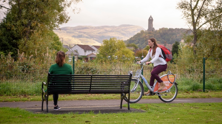 Woman cycling in Scotland with woman sitting on bench
