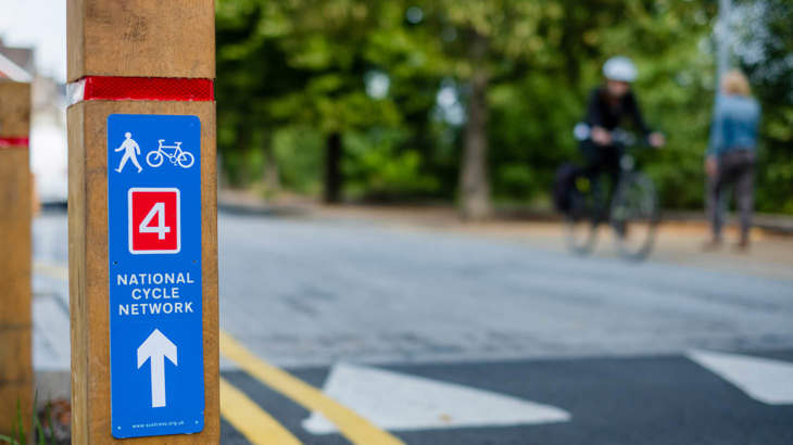 National Cycle Network Route 4 sign with two people on bikes in the background