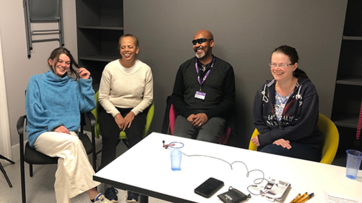 Three members of Croydon Vision are sat around a table talking with a Walk Wheel Cycle Trust member of staff about navigating urban environments (including Croydon) with a visual impairment.