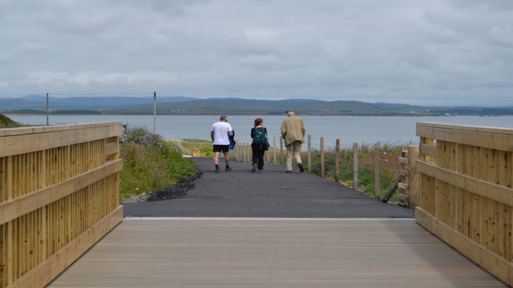 Three people crossing a bridge on the Loch Indaal Way.