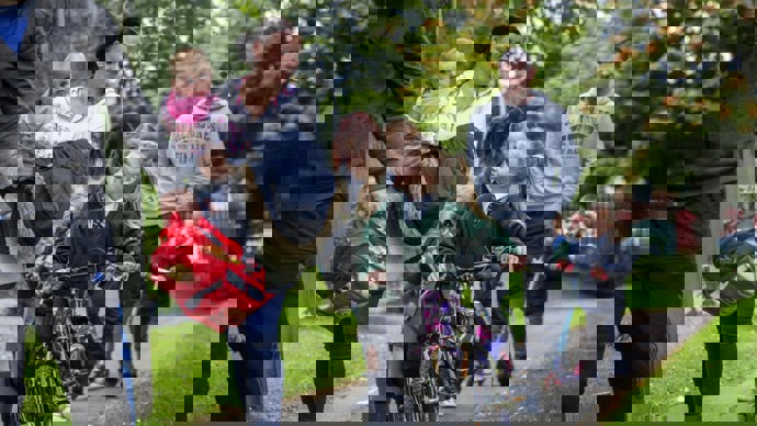 adults and children walking and scooting to school on footpath