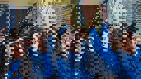 pupils in classroom raising their hands