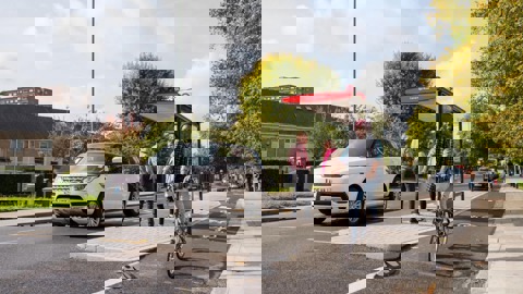 Man on bicycle on protected cycle lane, passing a bus stop