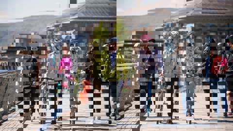 People walking and on bikes crossing bridge in urban setting