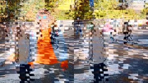 Woman walking on city street with people cycling in background
