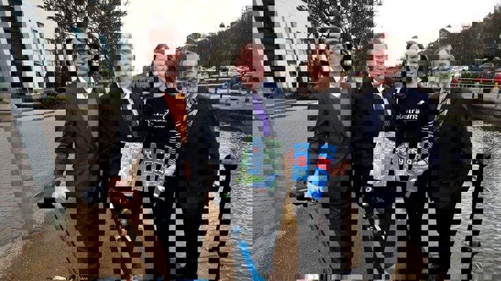 Walk Wheel Cycle Trust CEO Xavier Brice standing with three other people, holding a Paths for Everyone report and National Cycle Network signs