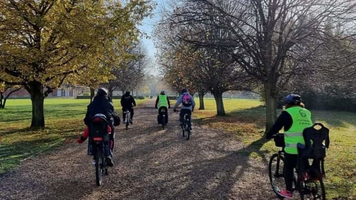 A group of people cycling through a woodland area on a sunny day all wearing helmets