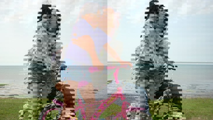 Mum hugging daughter on pink bike