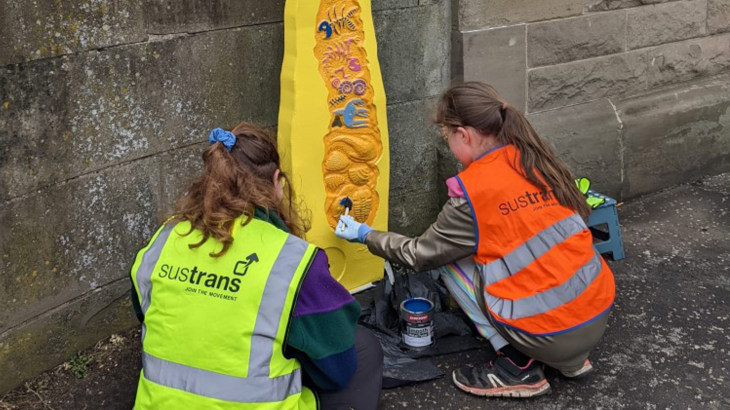 Aoife, the winner of the Girlguiding Scotland Milepost competition, paints her design on to a Millennium Milepost outside Arbroath Rail Station
