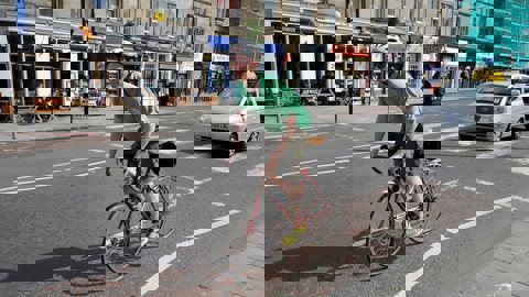Man cycling on road with car in background
