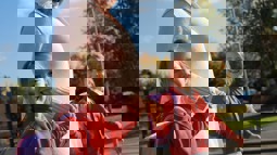 Mum walking to school, holding hands with her twin daughters smiling at the camera