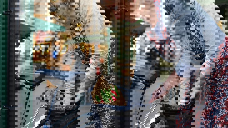 A woman packs her panniers on the side of her bike after doing some shopping