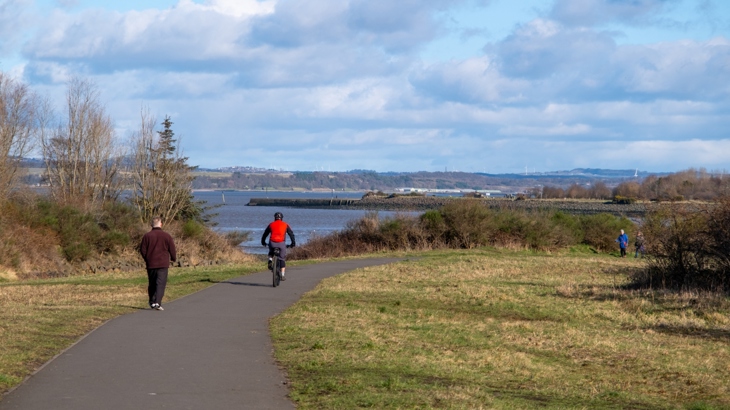People walking and cycling along National Cycle Network Route 7 at the Bo'ness Foreshore.