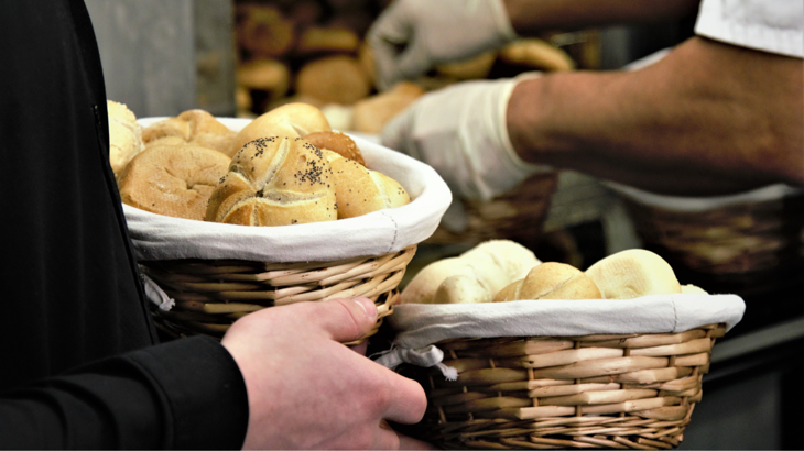 Basket of bread rolls being carried by a baker.