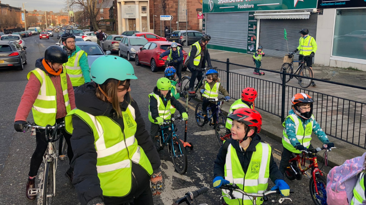 Children and adults chatting and smiling before they set off cycling to school on the bike bus