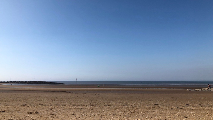 A flat sandy beach on The Wirral on a clear day