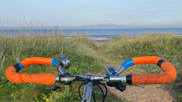 Bicycle handlebars in front of a beach on a clear day