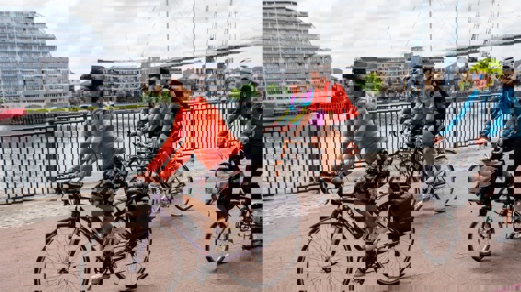 A group of people cycling along the river Thames in London 