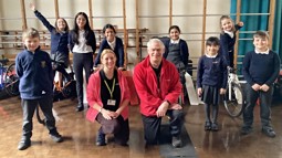 School children and Walk Wheel Cycle Trust schools officers Gemma and Eric smile at the camera in the school gymnasium after a Bike It activity.