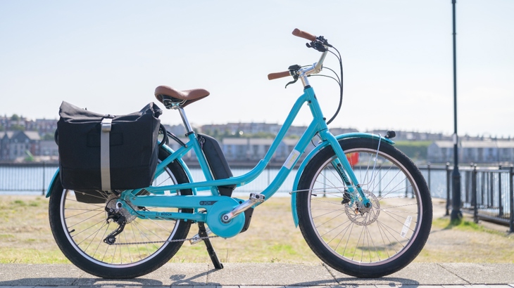 A turquoise e-bike parked in front of a waterfront in Barry, South Wales.