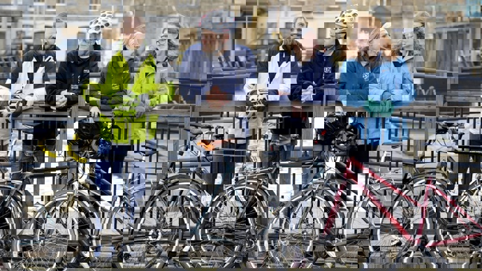 A group of colleagues, two male and two female, posing near a canal with their bicycles