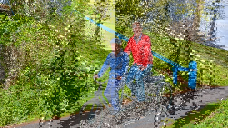 Man with Down Syndrome and older man riding tandem tricycle on traffic-free path