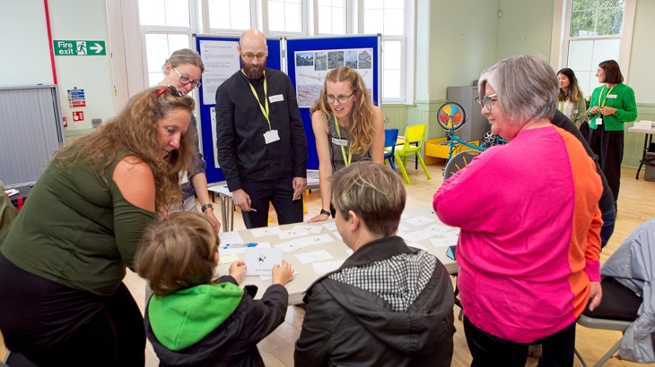 A young child explains their ideas for redesigning their local community to Walk Wheel Cycle Trust staff at a community engagement event