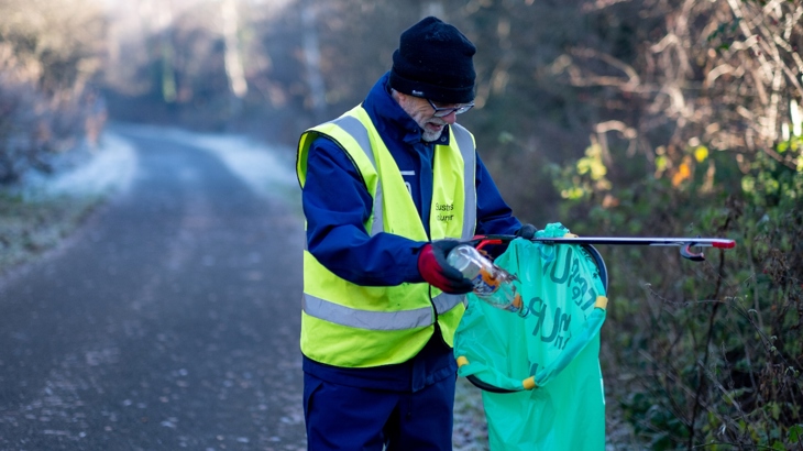 Member of the Thursday Squad putting litter into a picking bag hoop on the National Cycle Network in Renfrewshire.