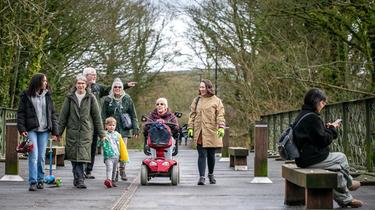 People walking and using a mobility scooter on a path