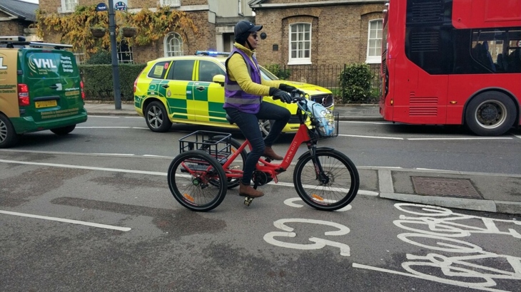 Riding upright trike in 2-way protected cycle lane, while an ambulance in 2-way mixed traffic, is passing a bus
