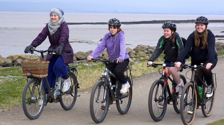 Four people cycling along the seafront promenade. 