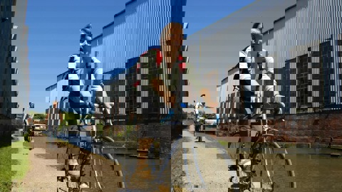 Two cyclists on canal towpath in industrial area