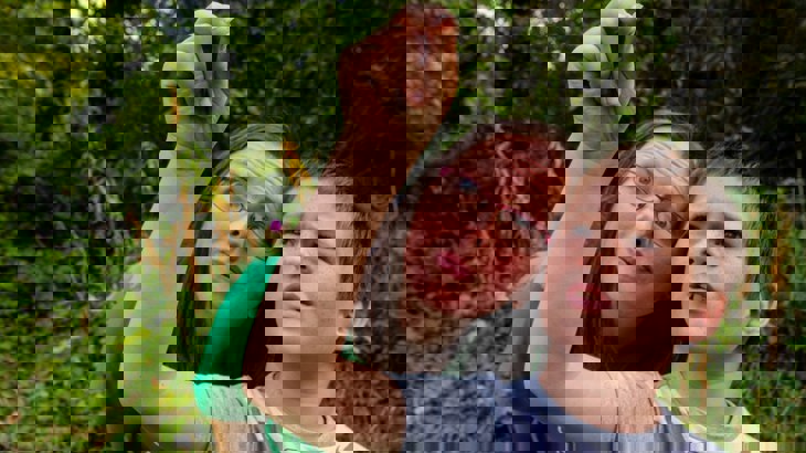 Woman in green t shirt and boy in grey t shirt inspecting something small that the boy is holding