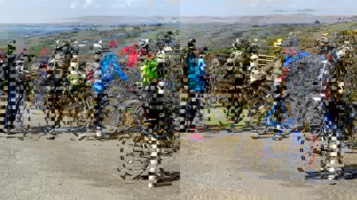 Eight cyclists on country road overlooking green hills in Devon