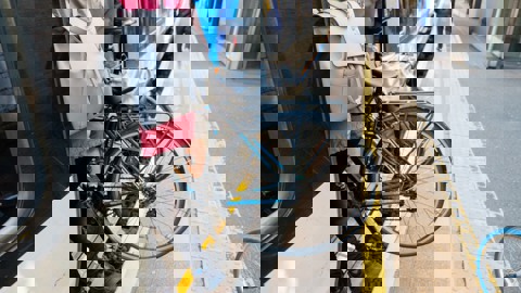 Bike being carried by person with blue backpack from train platform onto train