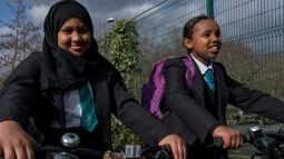 Two secondary school children riding bikes.