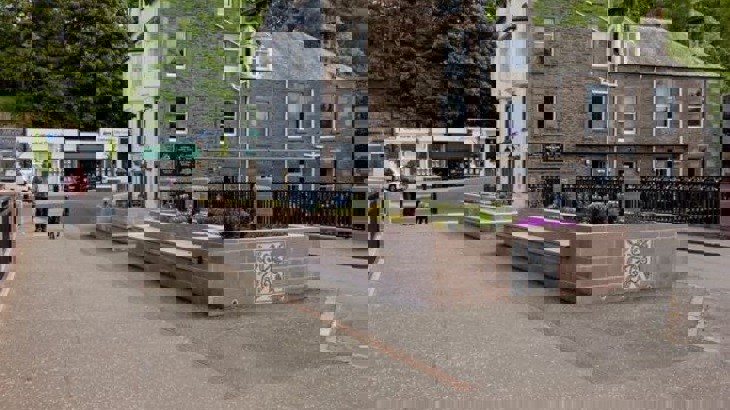 Bridge in town with pavement, road, pub building and dog walker