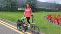 Woman in pink standing with a foldable bike in park