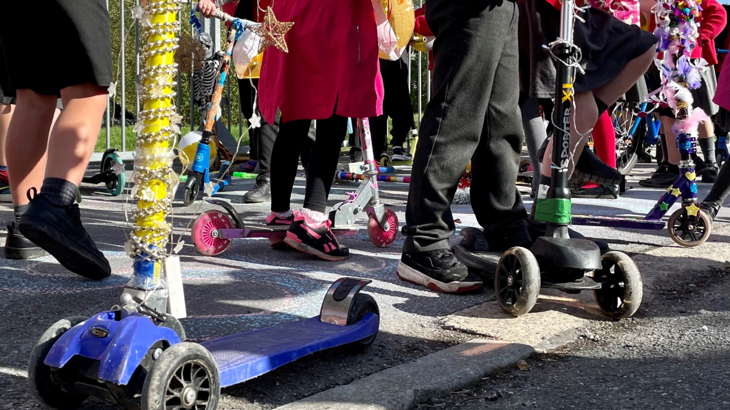 A group of children on decorated scooters, ready to start scooting to school.