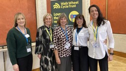 Group of women at formal event with charity roller banner in backdrop saying Walk Wheel Cycle Trust