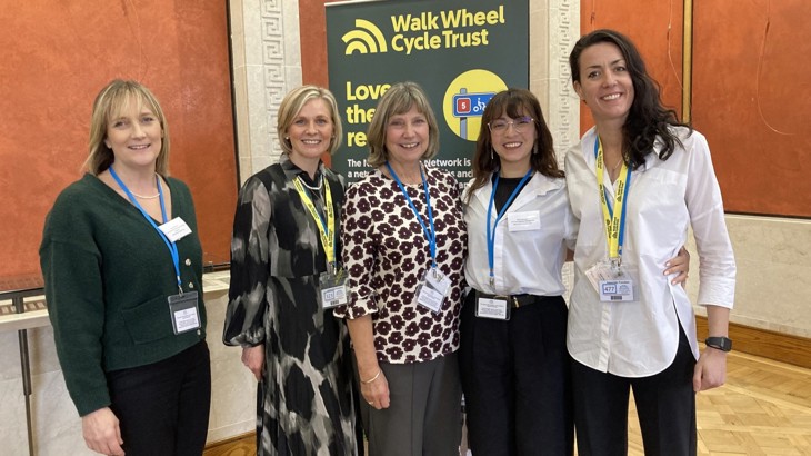 Group of women at formal event with charity roller banner in backdrop saying Walk Wheel Cycle Trust