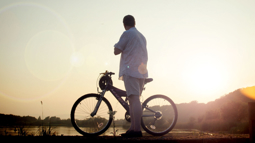 A person with their gravel bike standing in front of Loch Leven to watch the sunset.