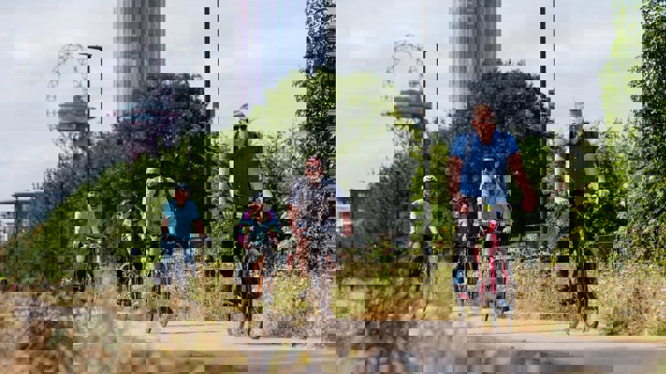 A group of people cycle along a Greenway in London