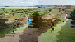 Cyclist in blue jersey following group of other cyclists on gravel path through countryside