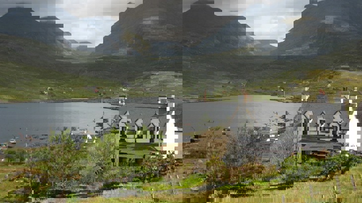 White house overlooking lake with mountains in the background