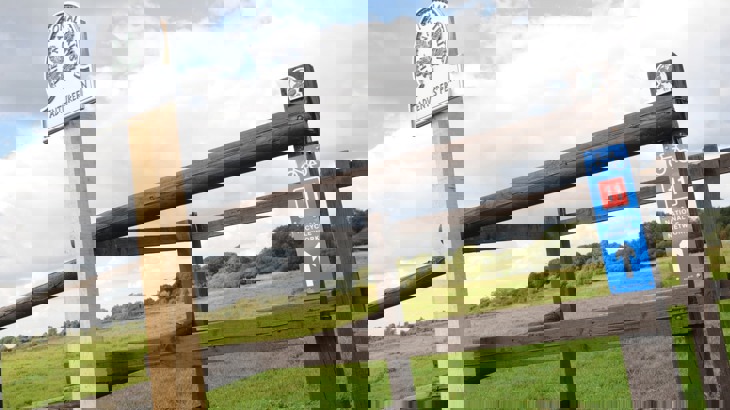 Fence with National Trust sign reading "Adventurers' Fen" and National Cycle Network Route 11 sign