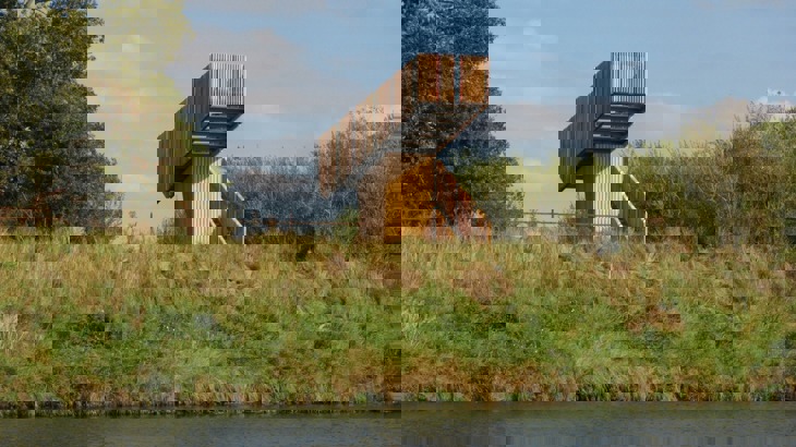Wooden viewing platform on grassy bank by waterway 