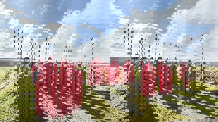 Red and grey metal sculptures shaped like Roman legionnaires with spears