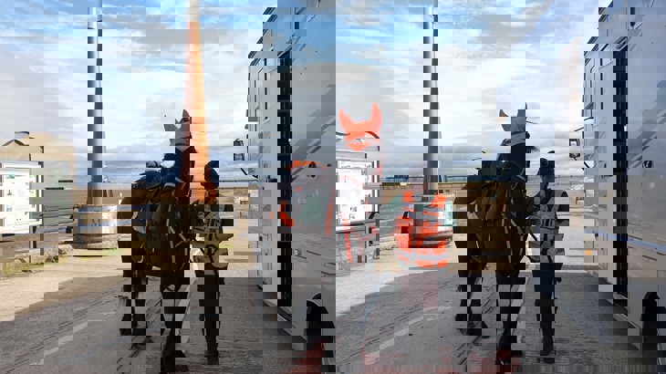 Sarah Bartlett Stands with her horse wearing high-vis clothing 